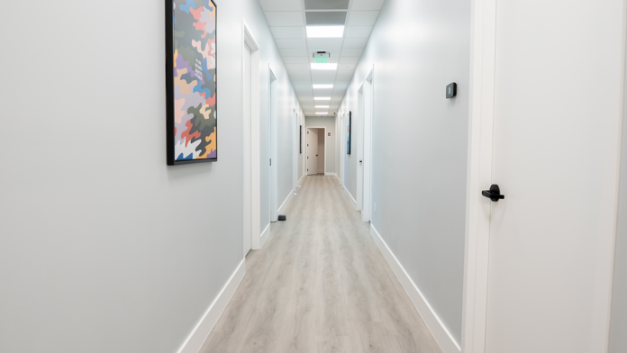 Long corridor inside the Boca Recovery Center clinic decorated with framed motivational art.