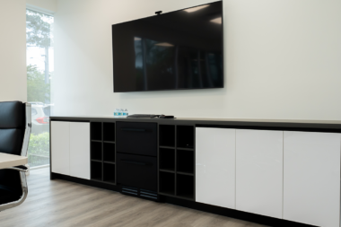 Modern office storage credenza and wall-mounted television inside a Boca Recovery Center meeting space.