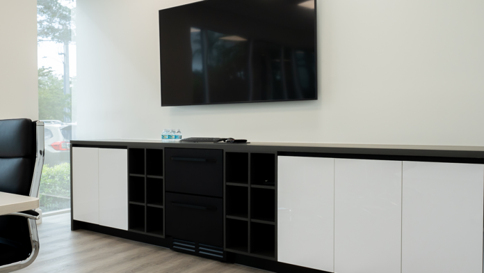 Modern office storage credenza and wall-mounted television inside a Boca Recovery Center meeting space.