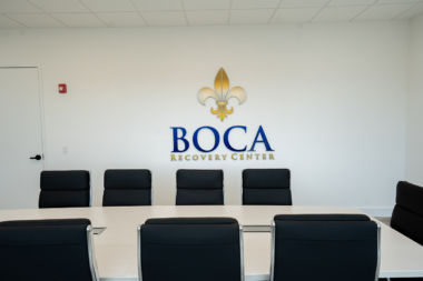 Black leather chairs facing the official Boca Recovery Center logo in the meeting room.