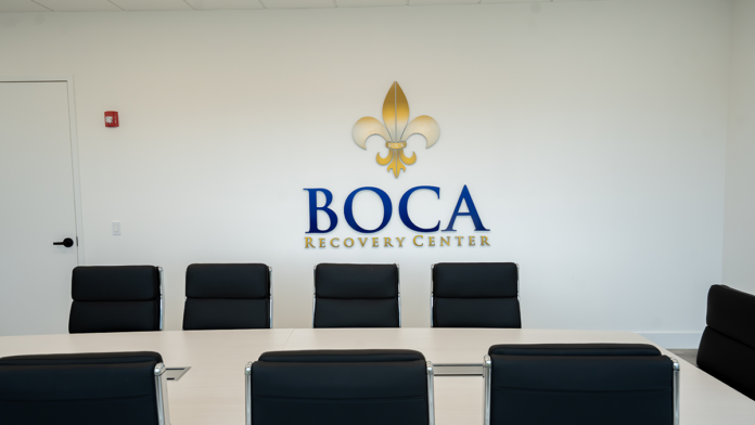 Black leather chairs facing the official Boca Recovery Center logo in the meeting room.
