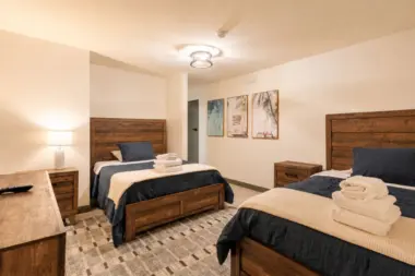 Shared bedroom at Recovery Beach with two wood-frame beds and beach-themed artwork