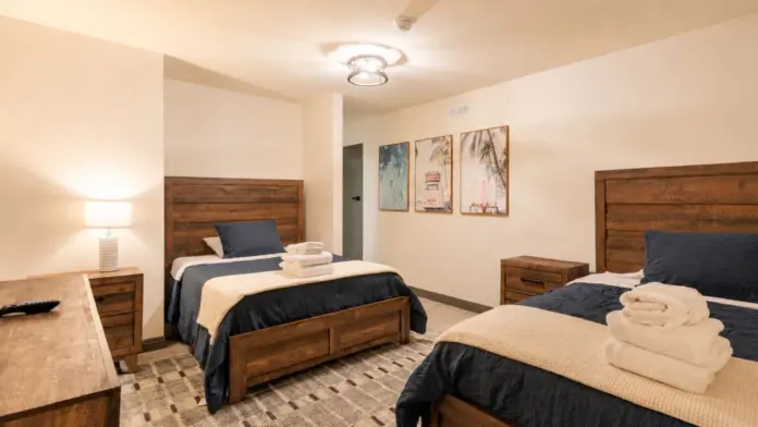 Shared bedroom at Recovery Beach with two wood-frame beds and beach-themed artwork