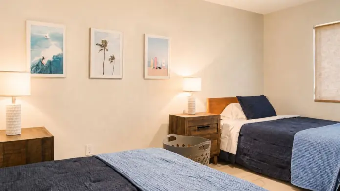 Shared bedroom at Recovery Beach with two beds, nightstands, and surf-themed wall art