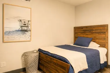 Single bedroom at Recovery Beach with a wood-frame bed and lifeguard tower photograph