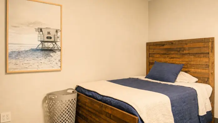 Single bedroom at Recovery Beach with a wood-frame bed and lifeguard tower photograph