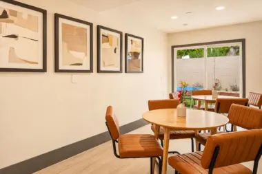 Casual dining area at Recovery Beach with round wood tables, leather chairs, and abstract framed art