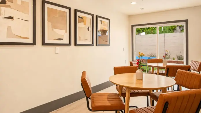 Casual dining area at Recovery Beach with round wood tables, leather chairs, and abstract framed art