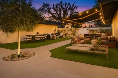 Courtyard at Recovery Beach at dusk with an olive tree, string lights, and multiple outdoor seating areas