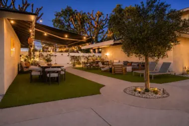 Courtyard at Recovery Beach at dusk featuring an olive tree, dining area, and lounge seating