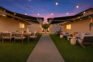 Courtyard at Recovery Beach at sunset with a walkway, string lights, and outdoor seating areas