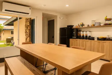 Communal dining and snack area at Recovery Beach with a long wood table and stocked pantry shelves