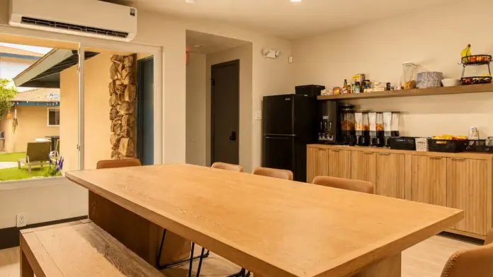 Communal dining and snack area at Recovery Beach with a long wood table and stocked pantry shelves