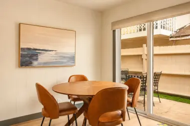 Dining nook at Recovery Beach with a round wood table, leather chairs, and sliding glass door to patio