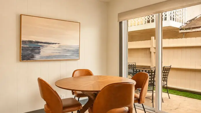 Dining nook at Recovery Beach with a round wood table, leather chairs, and sliding glass door to patio