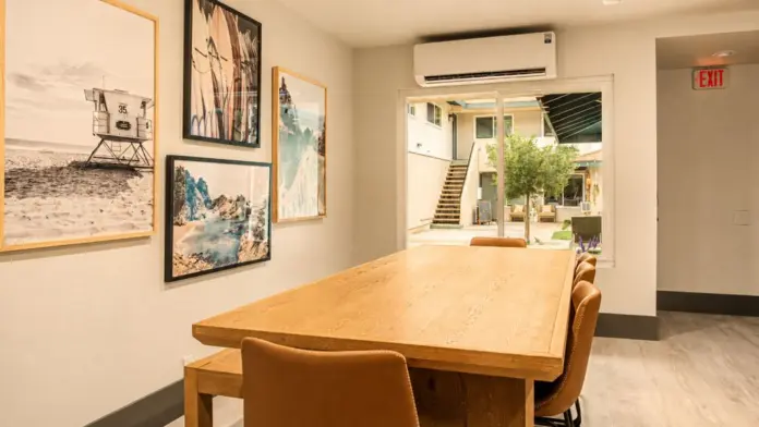 Dining room at Recovery Beach with wood table seating, gallery wall art, and sliding door view of the courtyard
