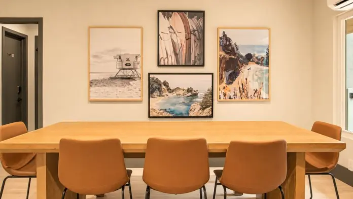 Dining room at Recovery Beach with a long wood table, leather chairs, and a gallery wall of coastal artwork