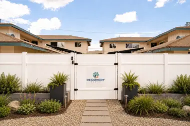 Daytime view of the white vinyl gated entrance to Recovery Beach Addiction Treatment Center in Garden Grove, CA