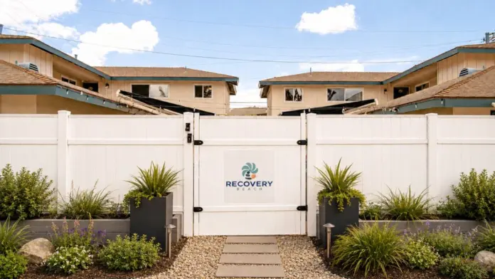 Daytime view of the white vinyl gated entrance to Recovery Beach Addiction Treatment Center in Garden Grove, CA