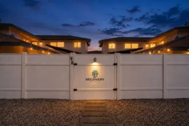 Evening view of the illuminated gated entrance to Recovery Beach Addiction Treatment Center in Garden Grove, CA