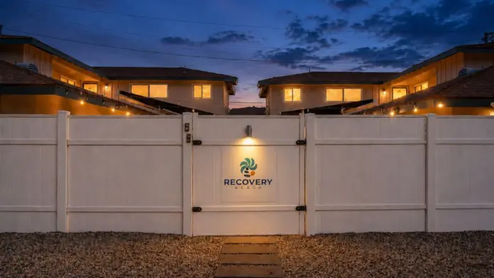 Evening view of the illuminated gated entrance to Recovery Beach Addiction Treatment Center in Garden Grove, CA