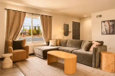 Living room at Recovery Beach with a gray sectional sofa, wood coffee table, and street-facing window
