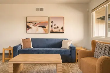 Living room at Recovery Beach with a navy sofa, wood coffee table, and coastal landscape artwork