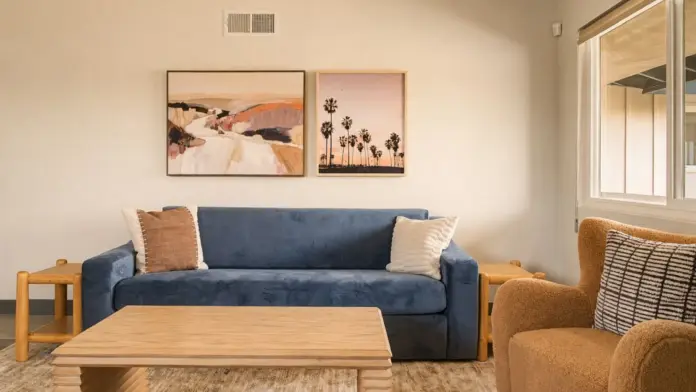 Living room at Recovery Beach with a navy sofa, wood coffee table, and coastal landscape artwork