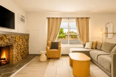 Living room at Recovery Beach featuring a stone fireplace, wall-mounted TV, and sectional sofa