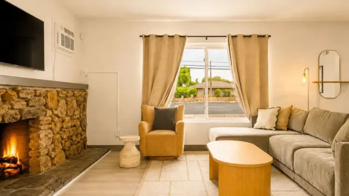 Living room at Recovery Beach featuring a stone fireplace, wall-mounted TV, and sectional sofa