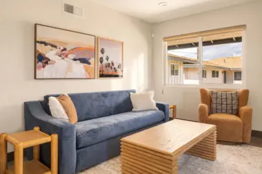 Living room at Recovery Beach with a navy sofa, wood coffee table, and view of neighboring rooftops