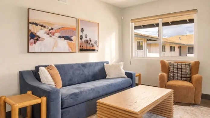 Living room at Recovery Beach with a navy sofa, wood coffee table, and view of neighboring rooftops