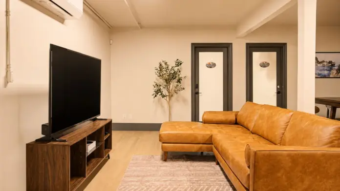 Common lounge at Recovery Beach with a tan leather sectional sofa and wall-mounted TV