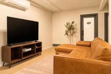Common lounge at Recovery Beach showing the leather sectional, entertainment console, and hallway doors