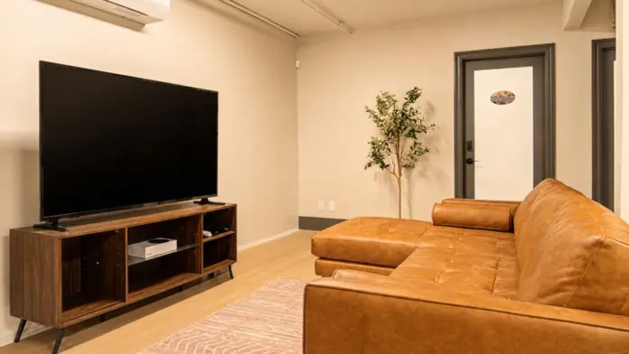 Common lounge at Recovery Beach showing the leather sectional, entertainment console, and hallway doors