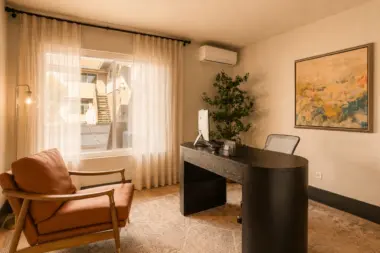 Private office at Recovery Beach with a dark wood desk, leather chair, and sheer curtains