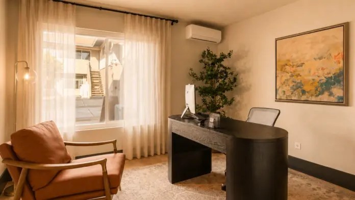 Private office at Recovery Beach with a dark wood desk, leather chair, and sheer curtains