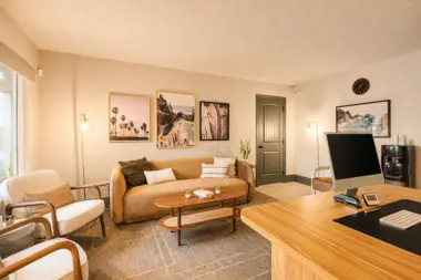 Office and lounge area at Recovery Beach with a tan sofa, armchairs, and coastal artwork