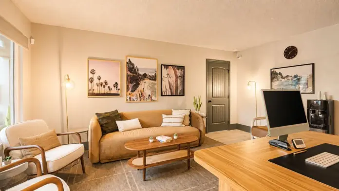 Office and lounge area at Recovery Beach with a tan sofa, armchairs, and coastal artwork