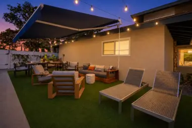 Patio at Recovery Beach at dusk with a retractable awning, lounge chairs, and string lights