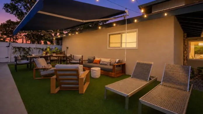 Patio at Recovery Beach at dusk with a retractable awning, lounge chairs, and string lights