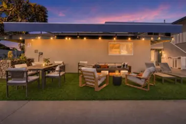 Patio lounge at Recovery Beach at dusk with a sectional sofa, string lights, and outdoor dining set