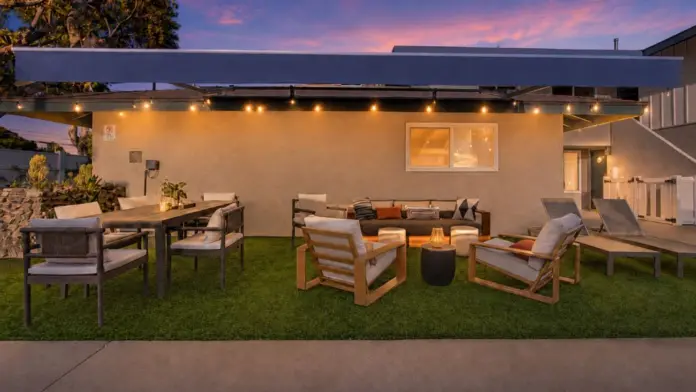 Patio lounge at Recovery Beach at dusk with a sectional sofa, string lights, and outdoor dining set