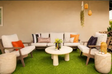 Outdoor patio lounge at Recovery Beach with cream sofas, wood armchairs, and artificial turf