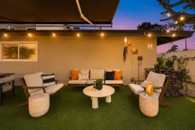 Outdoor seating area at Recovery Beach at dusk with cream armchairs, a round table, and hanging lanterns
