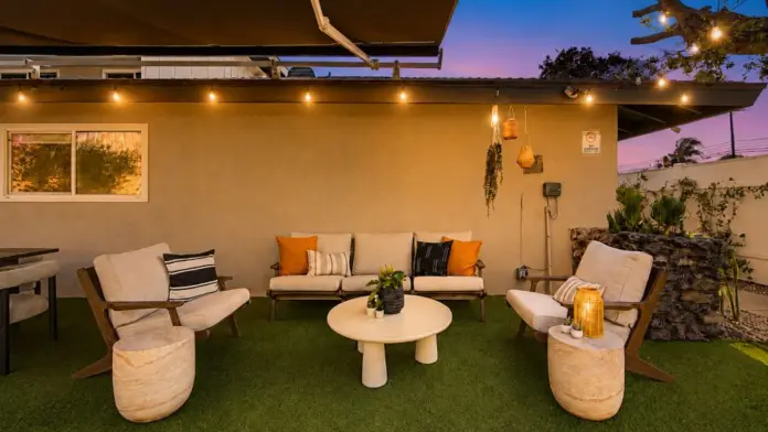 Outdoor seating area at Recovery Beach at dusk with cream armchairs, a round table, and hanging lanterns