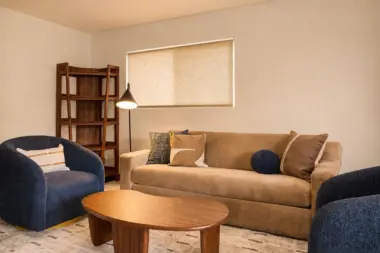 Sitting area at Recovery Beach with navy swivel chairs, a wood coffee table, and bookshelf