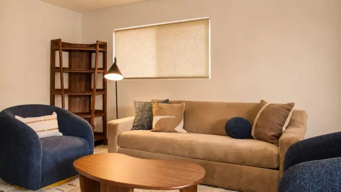 Sitting area at Recovery Beach with navy swivel chairs, a wood coffee table, and bookshelf