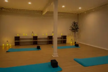Yoga studio at Recovery Beach with teal mats, meditation blocks, and warm ambient string lighting