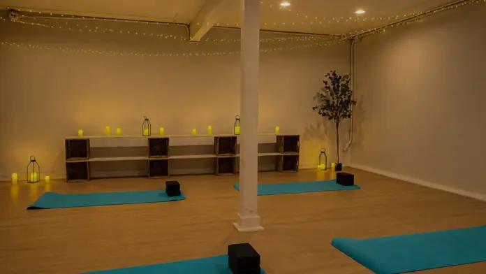 Yoga studio at Recovery Beach with teal mats, meditation blocks, and warm ambient string lighting